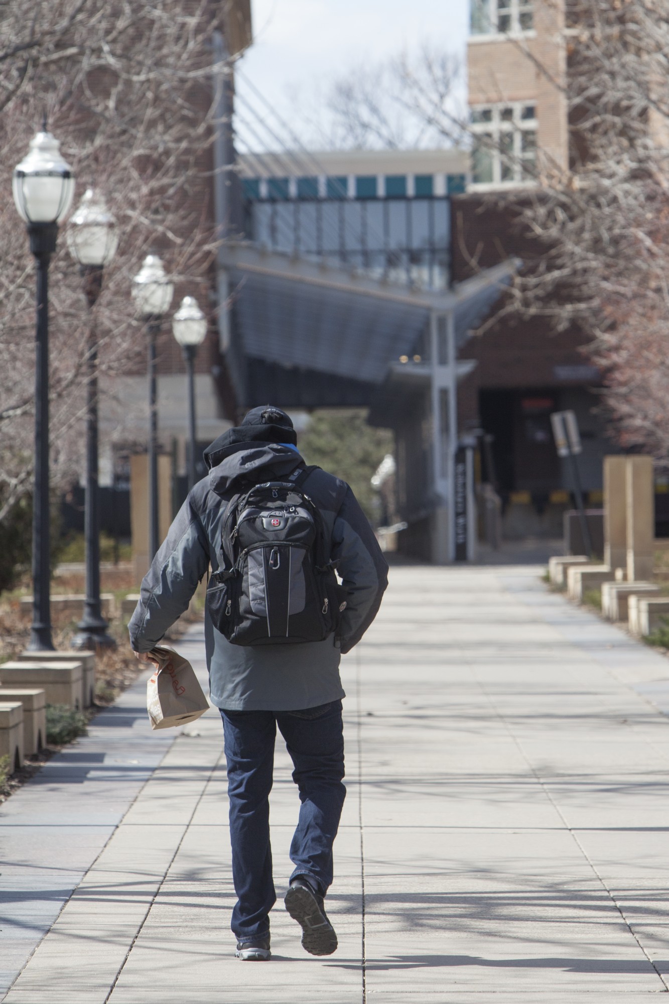 A passerby carries takeout as he walks along the Scholars Walk on Saturday, March 21. Many restaurants on and around campus remain open for takeout orders in an effort to maintain business through the COVID-19 health crisis.