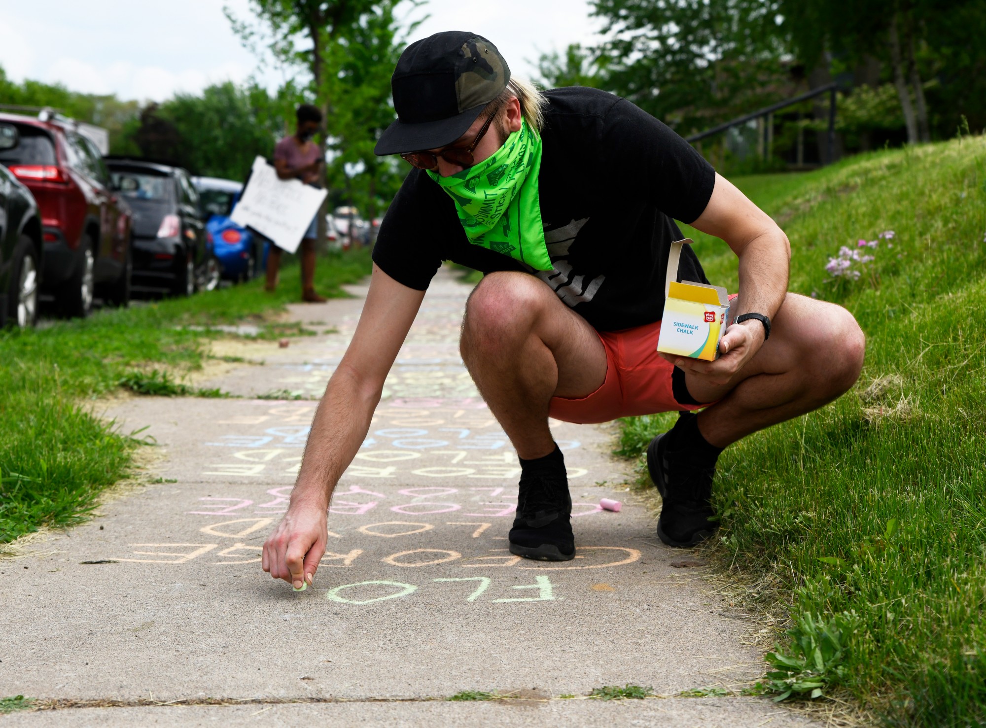 Francis Sullivan writes George Floyd’s name on the sidewalk where protesters walk towards Cup Foods on Chicago Ave S in Minneapolis on Tuesday, May 26.  Sullivan says that he does not do well in crowds but found an alternative way to support the protest. “I’m going to write [his name] until I run out of chalk,” Sullivan said. The protest was in response to the death of George Floyd in police custody. 