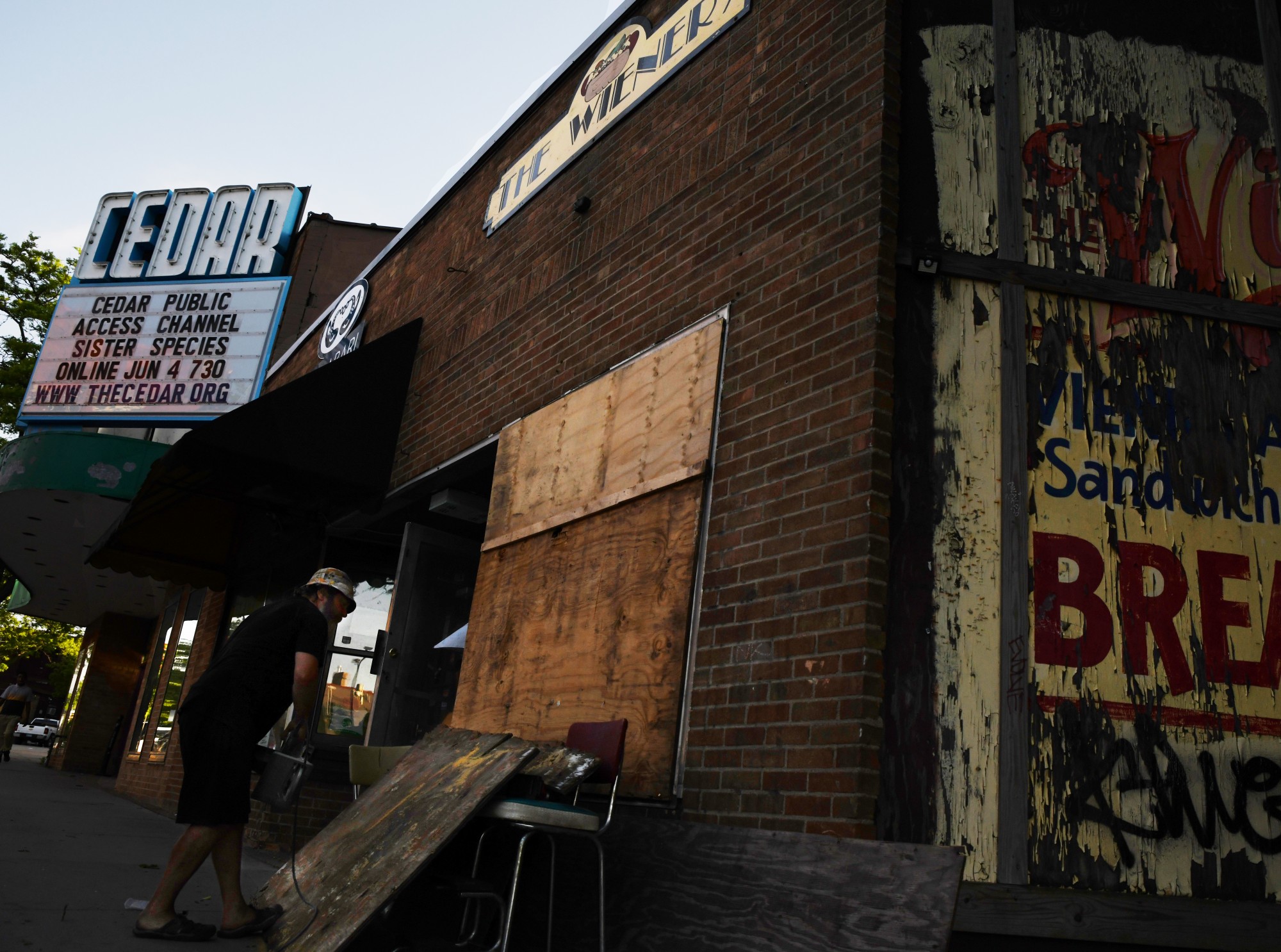 Pat Starr, owner of The Weiner, cuts plywood to board up the windows of his business in the Cedar-Riverside neighborhood on Thursday, May 28. 