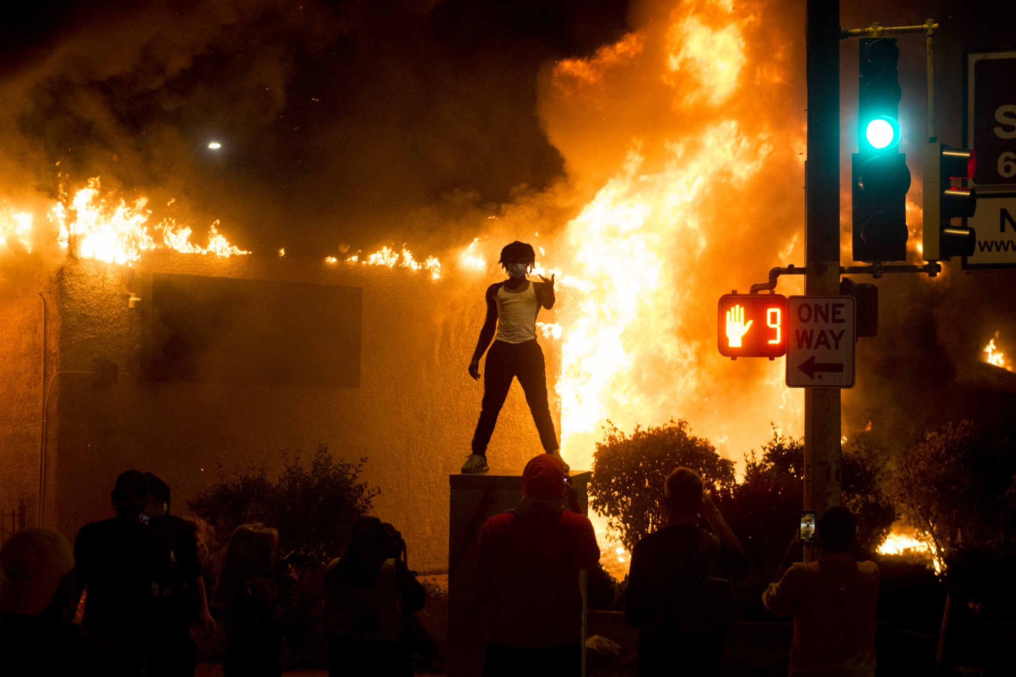 Photos are posed for in front of a burning building as part of riots near the 5th precinct in Minneapolis on Friday, May 29. 