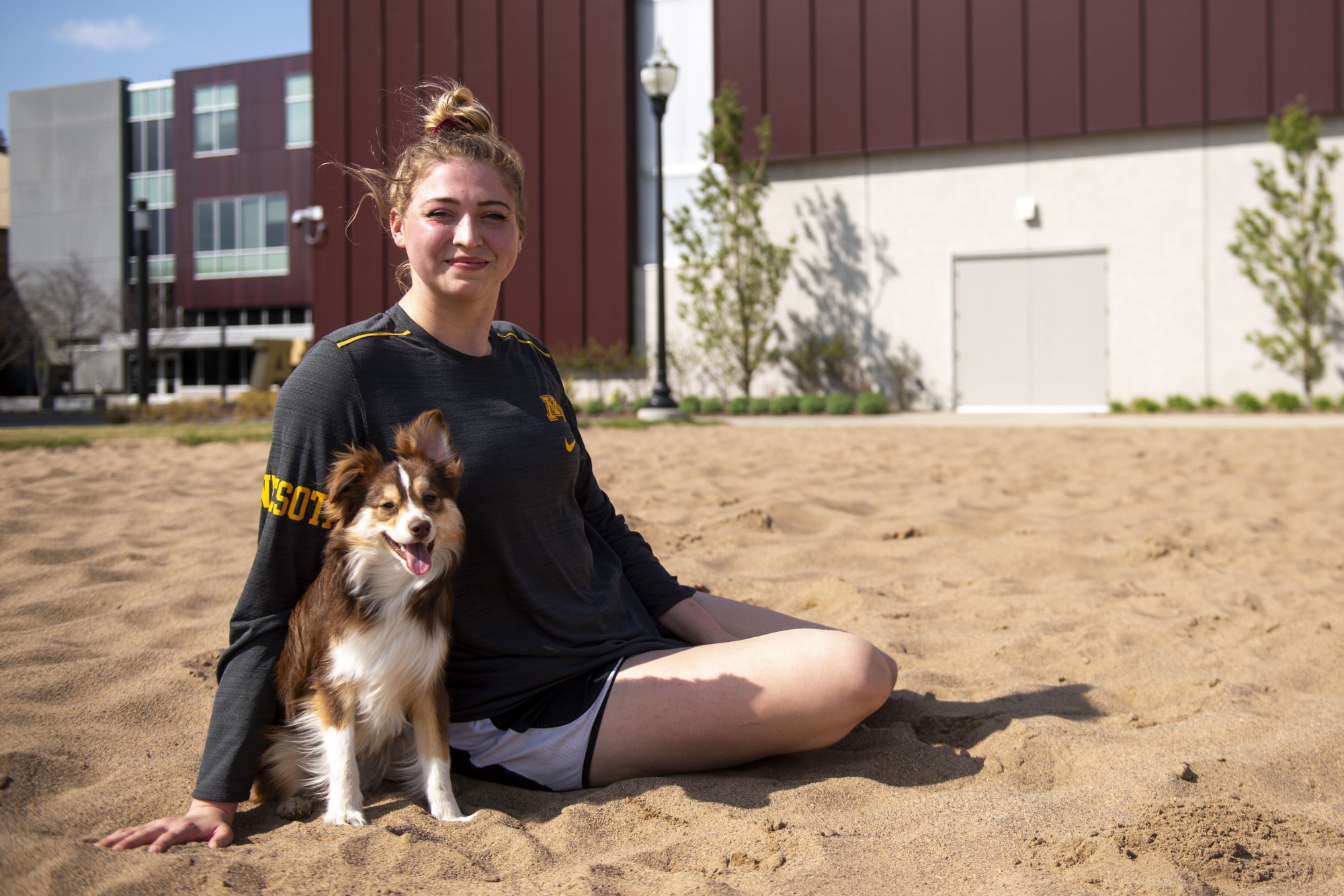 4:14 p.m.
Regan Pittman poses for a portrait with her dog, Earl, at the volleyball court in athletes village, now devoid of nets. Pittman, who still has one more year of eligibility with the volleyball team, is unsure of whether or not she will need to continue training. Earl, however, helps Pittman to smile and laugh everyday without even having to think about it. 