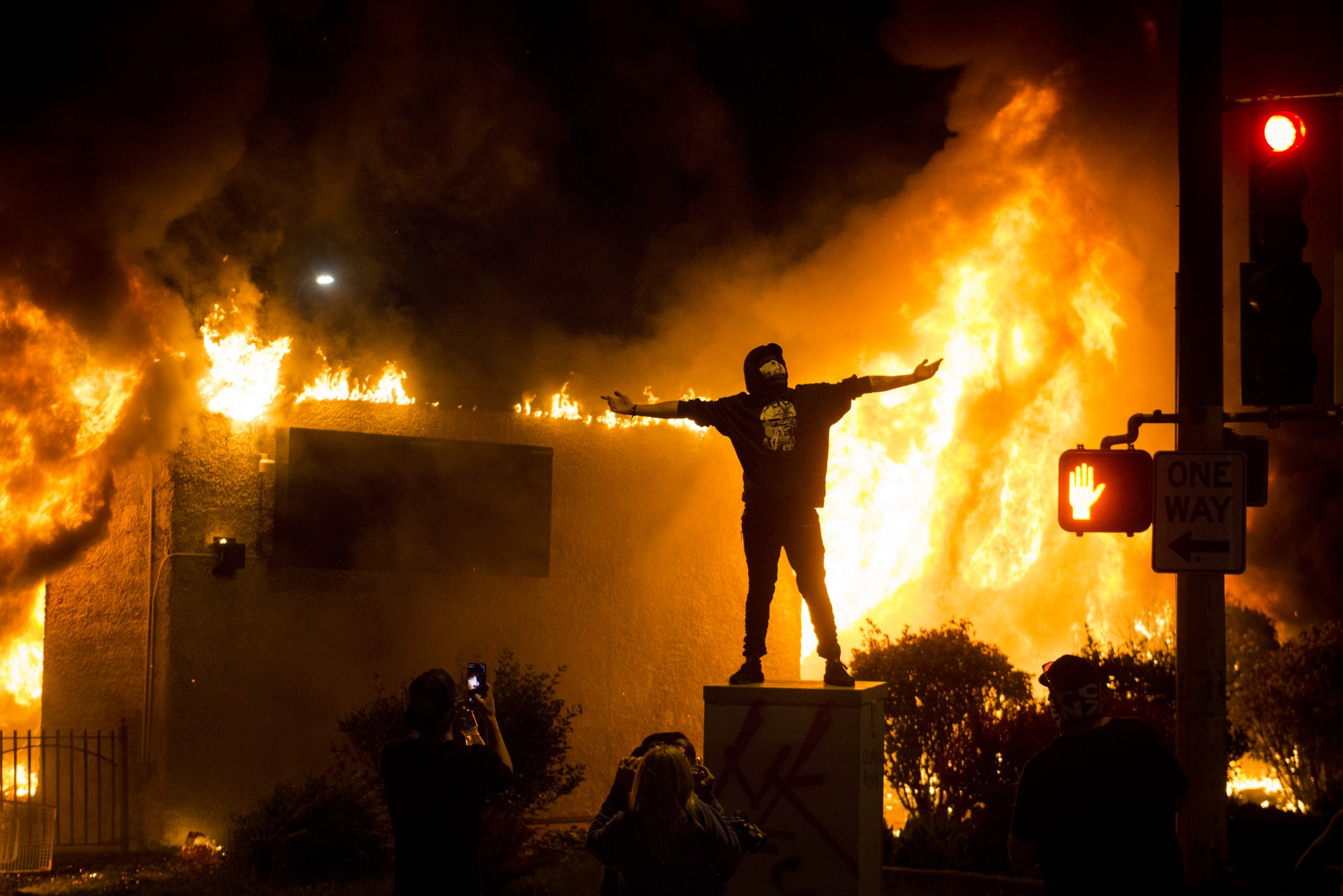 A person poses for photos in front of a burning building as part of riots near the Minneapolis 5th Police Precinct on Friday, May 29. 