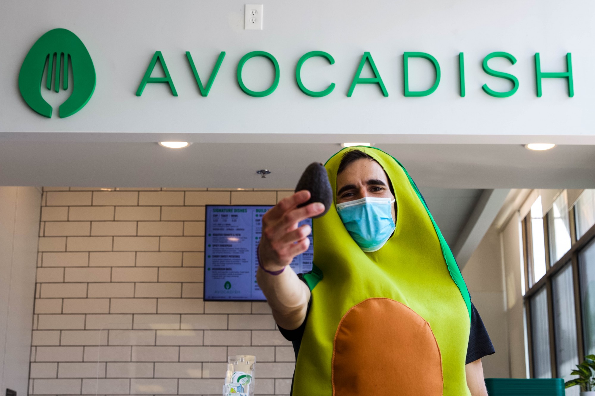 Alex Varouhas shows off an avocado while posing for a portrait in front of his newly opened restaurant, Avocadish, on Tuesday, June 30. Avocadish is located inside the University Food Hall in Dinkytown.