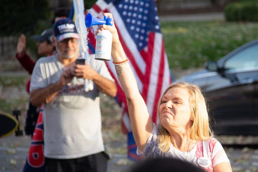 A woman uses an airhorn as counter-protesters show up to the rally of Trump supporters at the governor’s mansion on Nov. 7. The protest revolved around unproven claims of election interference and the state’s COVID-19 lockdown.