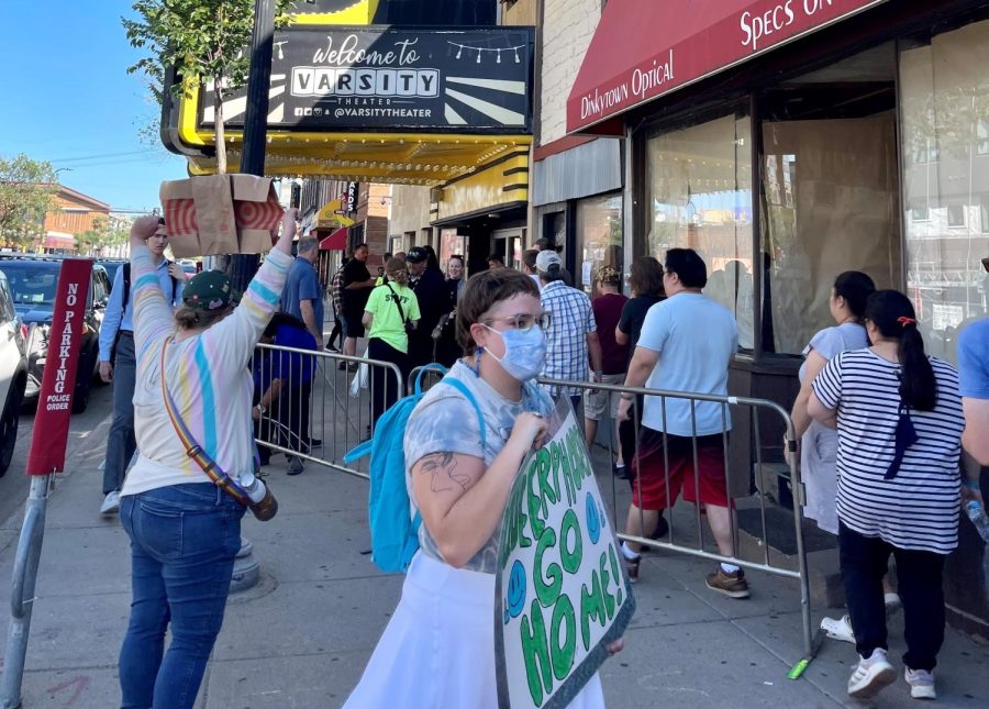 Protesters stood outside of Varsity Theater with signs while show attendees stood in line waiting for the show to start. 