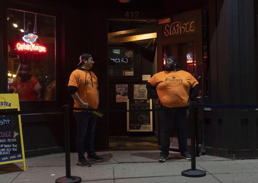 10:13 p.m. Bouncers stand outside Blarney Pub & Grill while students eat and drink inside. 