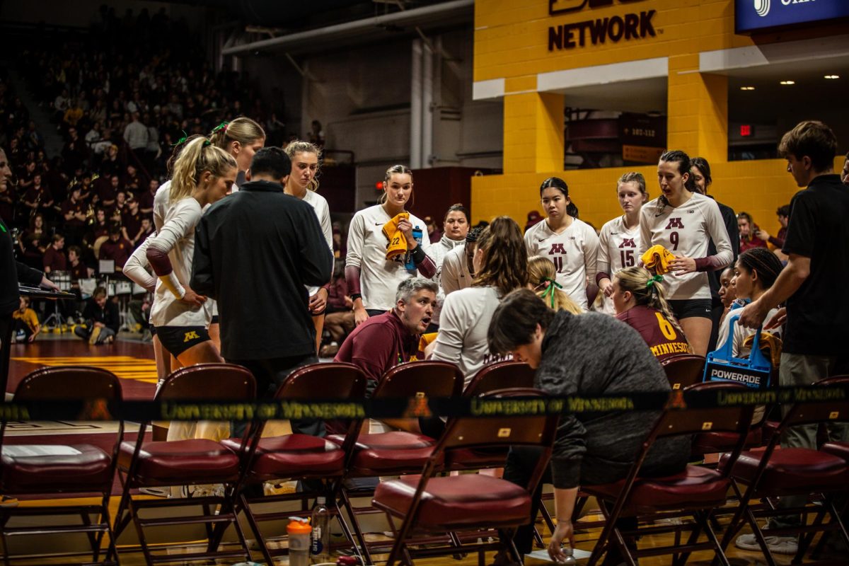 Head coach Keegan Cook (center) giving the Gophers volleyball team pointers during a break in play on Oct. 15, 2023.