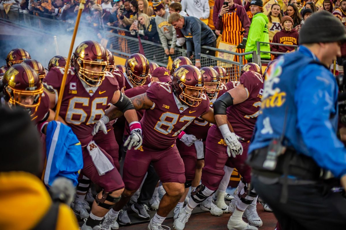 Martin Owusu (center) with Nathan Boe (left) leading a colony of Gophers out of the home team tunnel at Huntington Bank Stadium before playing Michigan Saturday, Oct. 7, 2023.