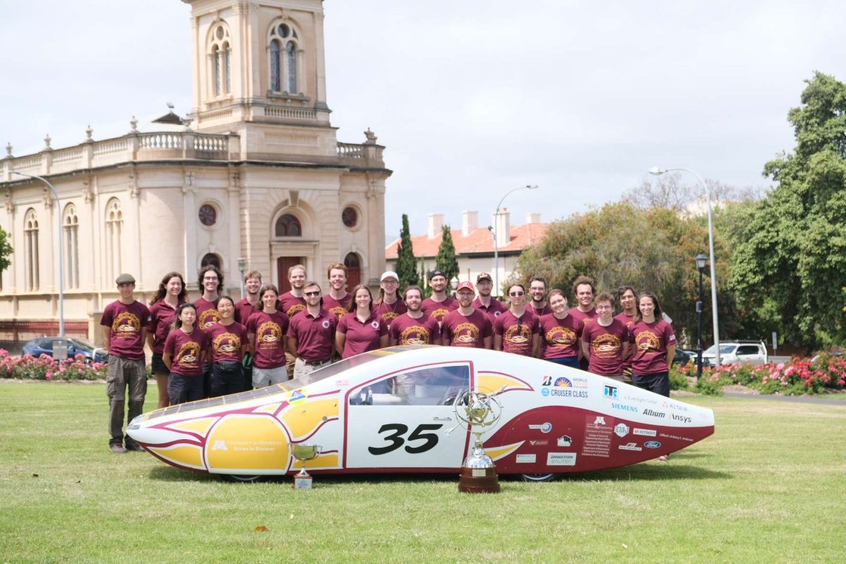 The+full+Solar+Vehicle+Project+team+poses+with+the+car+and+their+trophies.