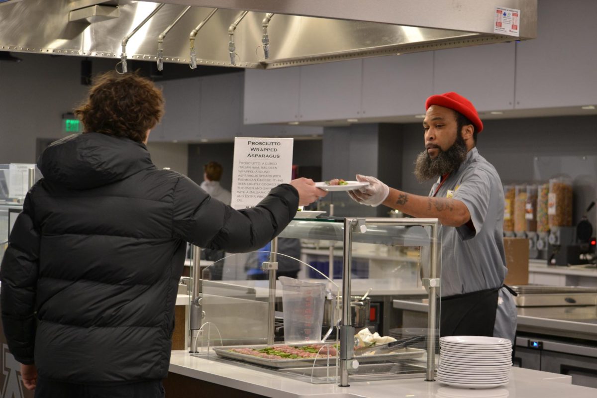 Charves Head, a chef at Athlete’s Village Nutrition Center, serves a student athlete dinner on Monday, Feb. 12, 2024.