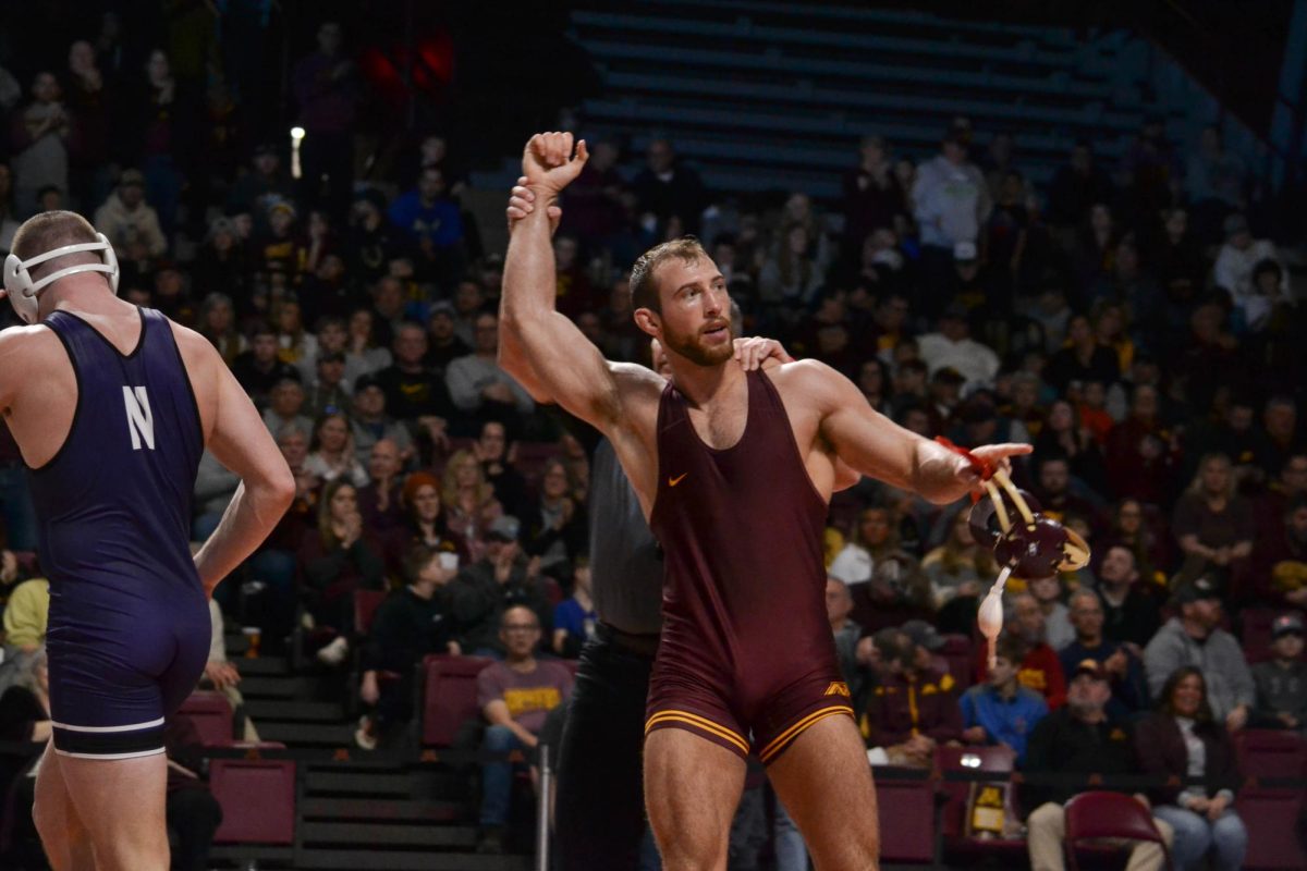 Garrett Joles raises his hand after beating his opponent from Northwestern on Sunday, February 4, 2024. The Gophers swept the Wildcats from Northwestern with a score of 39-0.