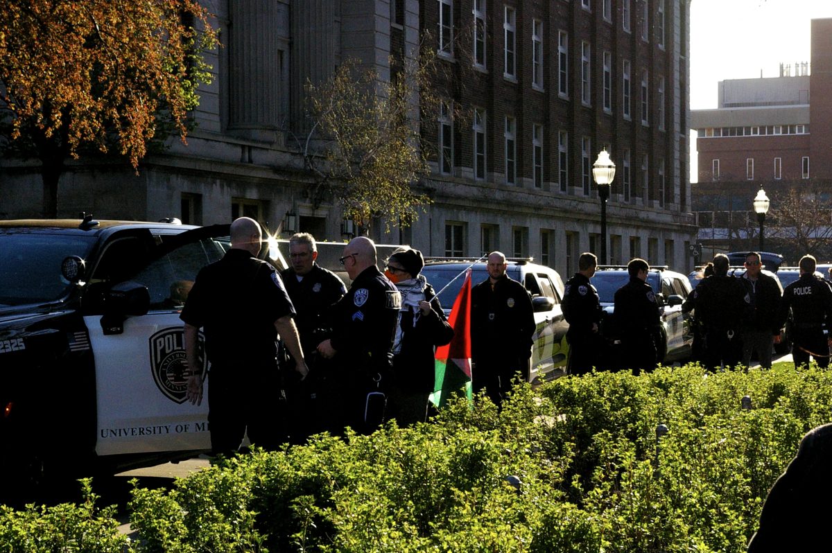 Police on Northrop Mall Tuesday morning. A protestor carries a Palestinian Flag.