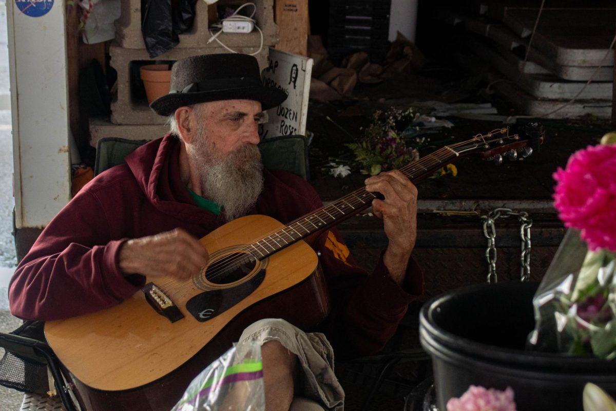 Florist Jim Bush plays the guitar at the Minneapolis Farmers Market.