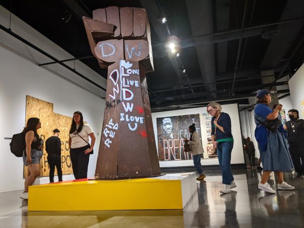 Jordan Powell-Karis’s iconic wooden fist sculpture is the centerpiece of this exhibition steeped in emotion.