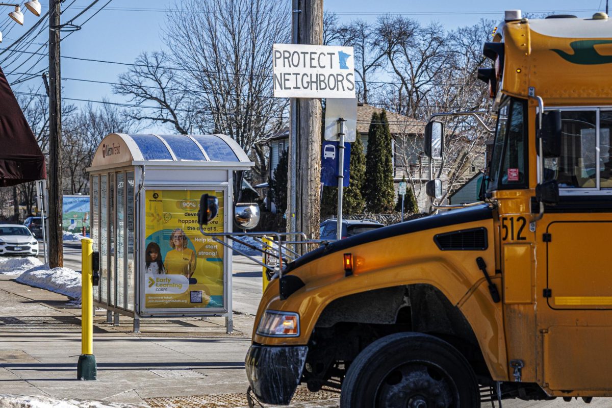 A sign reading “Protect Neighbors” is posted near a bus stop as a school bus passes on Friday, Jan. 30, 2026, in Minneapolis. | Courtesy of Kerem Yücel, MPR News