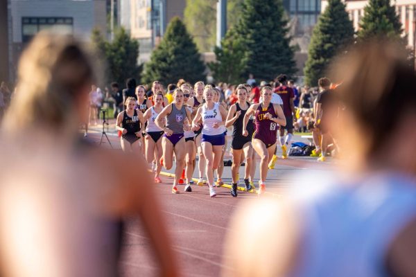 The 800 is run in two laps and there are multiple heats. Athletes in heat 2 look at the runners in heat 1 as they run in a pack and prepare to start their second and last lap of the race, April 22 2026.